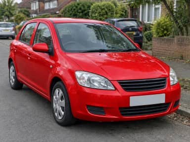 A parked grey hatchback on a street recolored to red, with the same windows, tyres, headlights and background (Red)