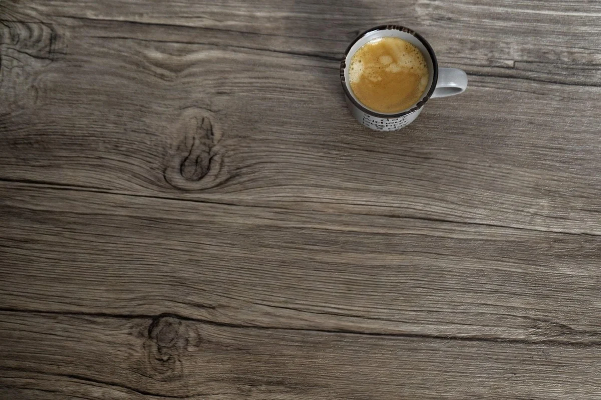 A keyboard and a phone removed from a desk, leaving the coffee cup